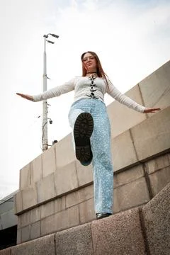 A young model in light-colored jeans walks around the city. Mild spring weather. Stock Photos