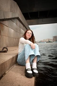 A young model in light-colored jeans walks around the city. Mild spring weather. Stock Photos