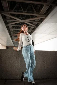 A young model in light-colored jeans walks around the city. Mild spring weather. Stock Photos