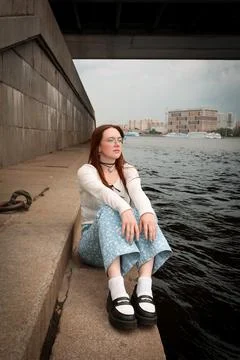 A young model in light-colored jeans walks around the city. Mild spring weather. Stock Photos