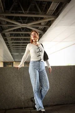 A young model in light-colored jeans walks around the city. Mild spring weather. Stock Photos