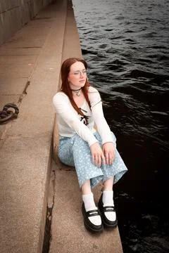 A young model in light-colored jeans walks around the city. Mild spring weather. Stock Photos