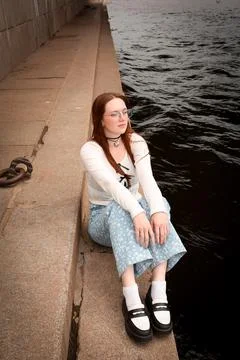 A young model in light-colored jeans walks around the city. Mild spring weather. Stock Photos
