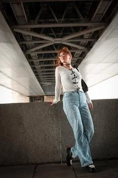A young model in light-colored jeans walks around the city. Mild spring weather. Stock Photos