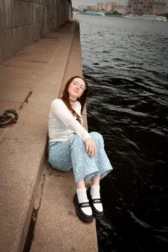 A young model in light-colored jeans walks around the city. Mild spring weather. Stock Photos
