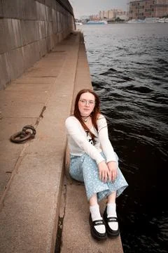 A young model in light-colored jeans walks around the city. Mild spring weather. Stock Photos