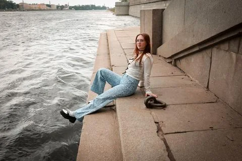 A young model in light-colored jeans walks around the city. Mild spring weather. Stock Photos