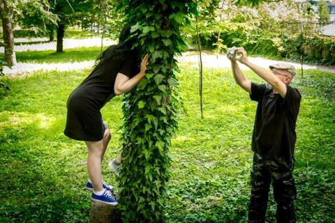 Young model poses for creative senior photographer on overgrown tree frame Stock Photos