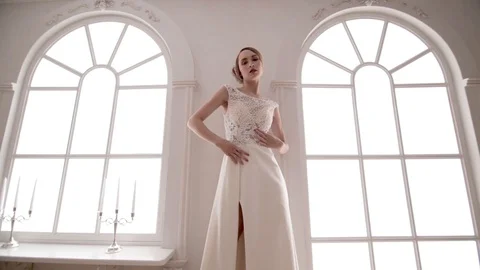 Young model posing in wedding dress between windows Stock Footage 104576894