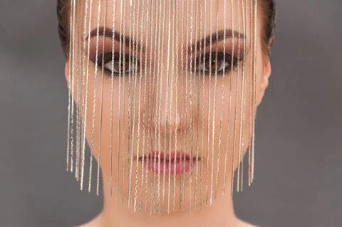 Young model with professional make up closing her face with metal mask Foto stock