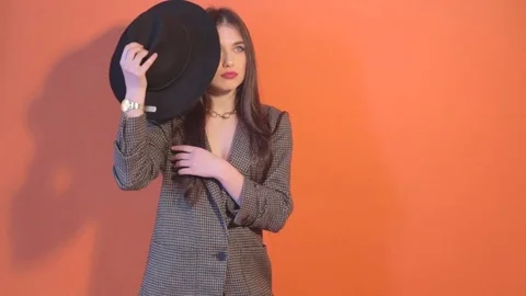 Young model puts on a hat and posing near the wall Stock Footage 73345837