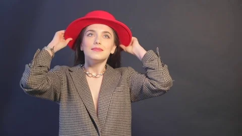 Young model puts on a red hat and posing near the wall Stock Footage 73362569