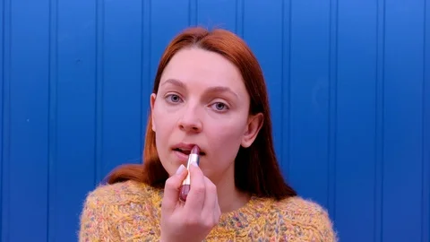 Young model putting on some makeup, using lipstick to color hel lips.  Stock Footage 124084422