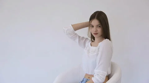 Young model sits in comfortable chair and practices in posing Stock Footage 67387406