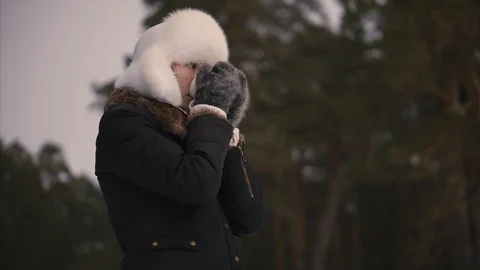 Young model in winter white hat enjoys the snow and drinks hot beverage Stock Footage 101855215