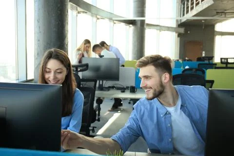 Young modern colleagues working while spending time in the office. Stock Photos