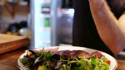 Young modern cook prepares steak with salad 動画素材 78743891