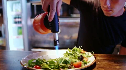 A young modern cook warms up a dish with a gas burner Stock-Footage 78742711