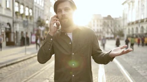 Young, modern handsome man talking on the phone on the street on a sunny day Stock Footage 152477774