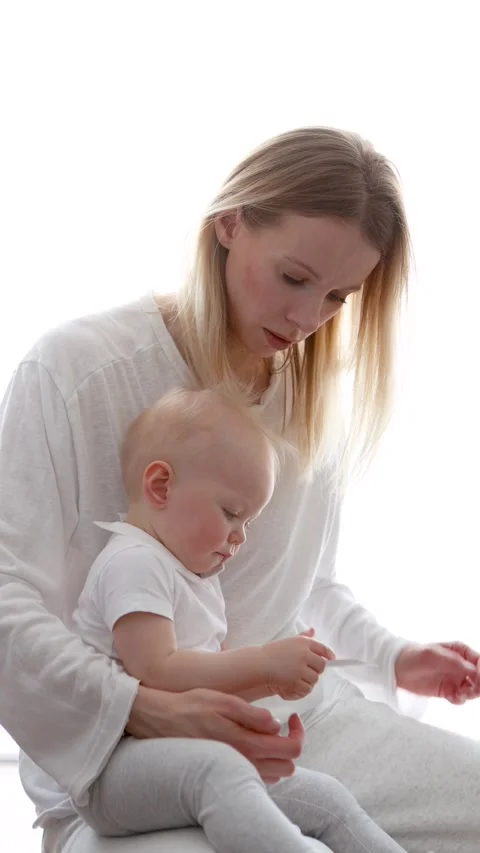 Young mom developing fine motor skills with baby while playing at home on white Stock Footage 311755355