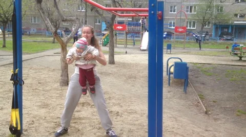 Young mom doing squats whith baby outdoors Stock Footage 62795124