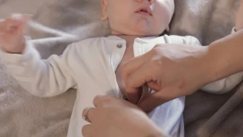 Young mom dressing her little newborn son on the bed. 스톡 동영상 108685396