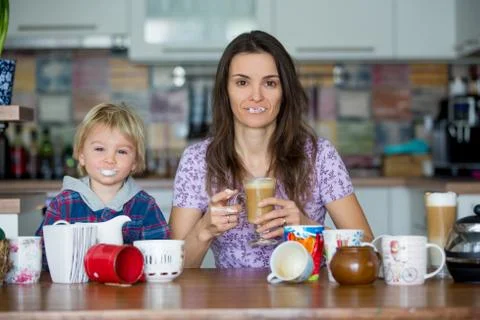 Young mom, drinking many coffees in the morning with her toddler child Stock Photos