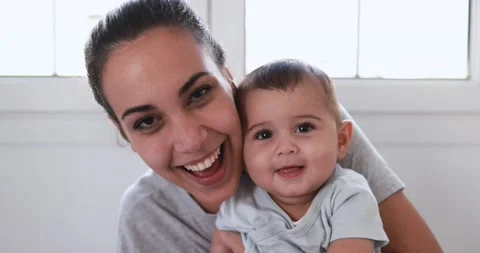 Young mom having fun with her baby at home smiling on camera Stock Footage 168816771