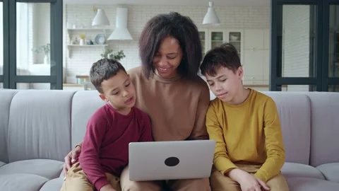 Young mom sitting close to her sons, surfing on laptop, making online purchases Stock Footage 197468029