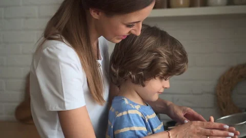Young mom teaching son to cook food and standing at table in apartment kitchen. Stock Footage 161121438