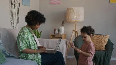 Young Mom Working on Laptop and Helping Toddler Modeling Clay in Living Room Stock Footage 334121610