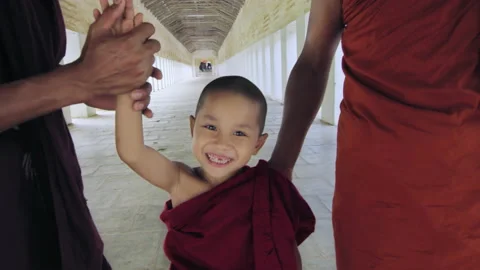 Young monk boy in ancient passage way doing high five while walking in temple. B Stock Footage 201095119
