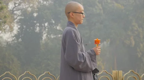Young monk in grey robe prays with praying wheel,Kushinagar,India Video stock 65307057