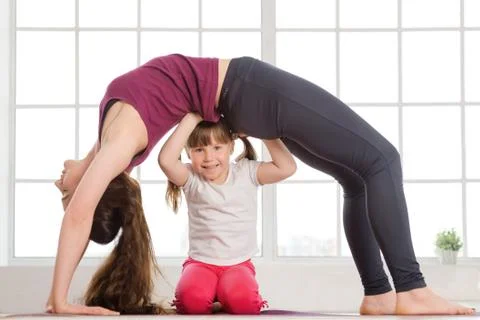 Young mother and daughter doing yoga exercise Stock Photos