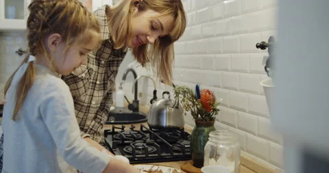 Young mother and daughter having fun baking cookies in the kitchen together Stock Footage 146116653