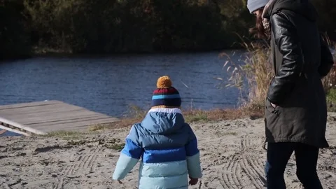 Young mother and her small child standing on a pier on the lake Stock Footage