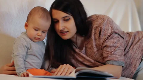 A young mother and a small child reading a book. Slow motion shot. Video stock 89772653