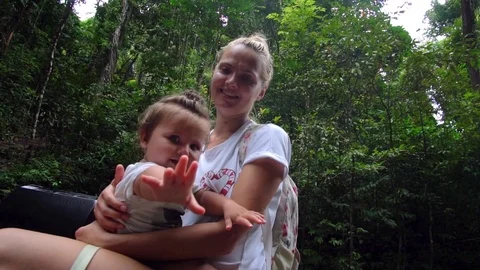 Young mother and small daughter resting in a forest. Beautiful child playing Stock Footage
