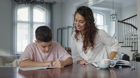 Young Mother And Son At The Table. Boy Writes In Notebook. He Does His Homework. Stock Footage 146468437