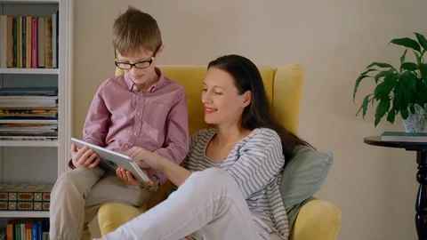Young mother and son using tablet while sitting in armchair in apartment room Stock Footage 128972834