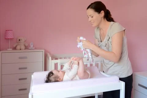 Young mother changes clothes on her baby Stock Photos