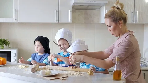 Young mother cooking in the kitchen with the children. family having fun and Stock Footage