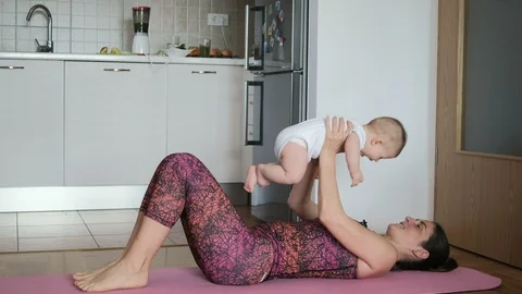 Young mother doing yoga or sport with baby in the kitchen at home Stock Footage 102700565
