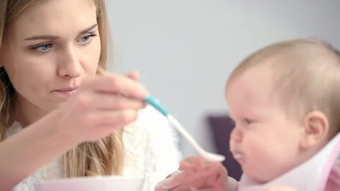 Young mother feeding baby. Young mom feed child with spoon Stock Footage