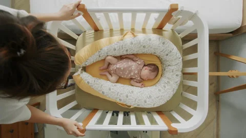 Young mother gently stroking sleeping baby in crib at home, top view Stock Footage 237460496