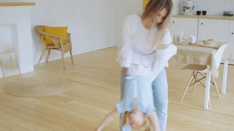 Young mother has fun with little daughter, holding her and dancing, tossing kid Stock Footage 194692547