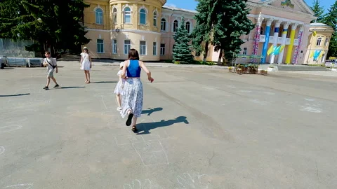 A young mother having fun and playing hopscotch game on the asphalt with her Stock Footage 338323002