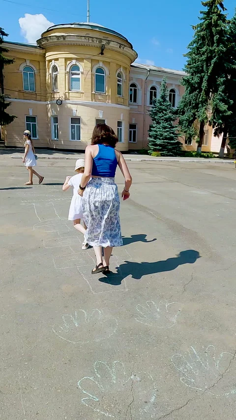 A young mother having fun and playing hopscotch game on the asphalt with her Stock Footage 338397196