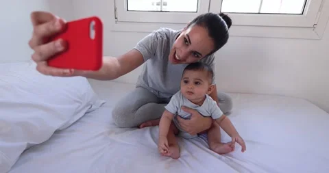 Young mother having fun doing video call with her baby at home Stock Footage 168815943