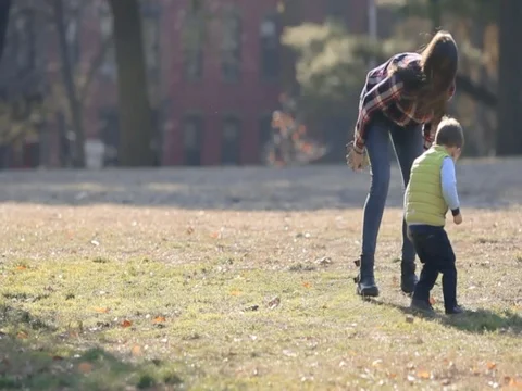 Young mother having fun with her kid son in autumn park, playing with leaves Stock Footage 74006228